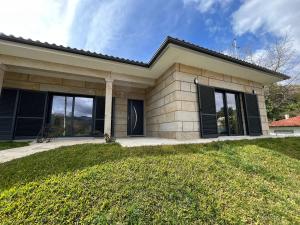 una casa con finestre con persiane nere e un cortile di Casa da Falperra a Arcos de Valdevez
