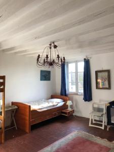 sypialnia z łóżkiem z niebieskimi zasłonami i żyrandolem w obiekcie Sainte-Suzanne gîte de LA FERME calme et tranquille w mieście Les Baux-de-Breteuil