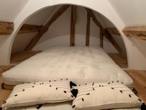 a bed with two pillows in a room with an attic at Grange Rousselin in Bachivillers