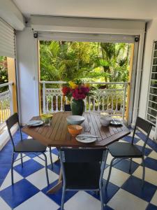 einen Holztisch mit Stühlen und eine Vase mit Blumen auf der Veranda in der Unterkunft Courbaril Village in Les Trois-Îlets