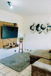 a living room with a flat screen tv and a couch at Excelente Apto a 2 km CENTRINHO TURÍSTICO in Campos do Jordão
