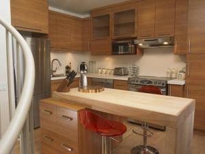 una cocina con armarios de madera y una barra con sillas rojas en Loft au coeur du Vieux-Québec, en Quebec