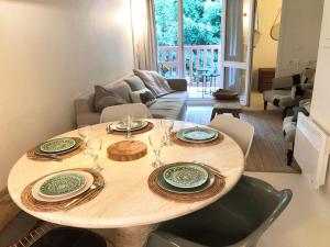 a wooden table with plates and wine glasses on it at Appartement 2 chambres COULEUR DUNE, piscine, parking gratuit in Le Touquet-Paris-Plage