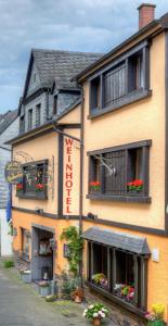 a large yellow building with flowers in the windows at Weinhotel Hubertus Garni in Klotten