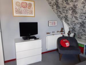 uma sala de estar com uma televisão e uma cadeira em La petite mouette em Ouistreham