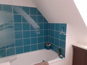 ein blau gefliestes Bad mit einer weißen Badewanne in der Unterkunft La petite mouette in Ouistreham