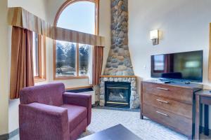 a living room with a chair and a fireplace at Chateau Canmore in Canmore