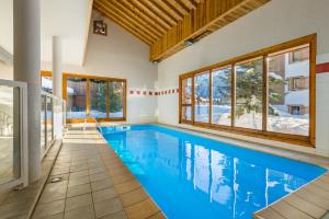 une piscine intérieure d'eau bleue dans une maison dans l'établissement Lagrange Vacances Les Fermes de Samoëns, à Samoëns