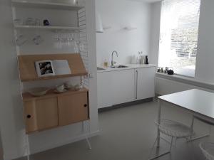 a white kitchen with a sink and a counter at Maan B&B + Galerie in Kortgene