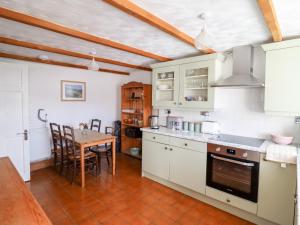 a kitchen with white cabinets and a table in it at Trigfa in Blaenau-Ffestiniog