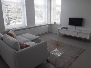 a white living room with a couch and a tv at Maan B&B + Galerie in Kortgene