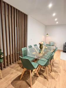 a dining room with a glass table and green chairs at Cunha's Apartment - city center in Guimarães