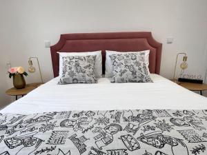 a bed with a black and white blanket and pillows at Cunha's Apartment - city center in Guimarães