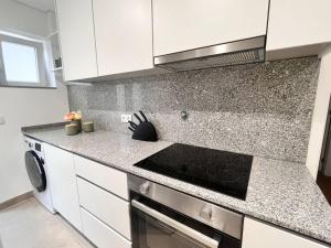 a kitchen with white cabinets and a stove top oven at Cunha's Apartment - city center in Guimarães +13 photos