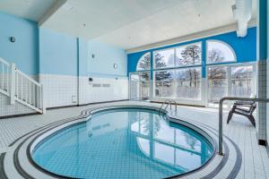 an indoor swimming pool with blue walls and windows at Chateau Canmore in Canmore