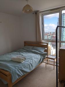 a bed in a bedroom with a large window at 2 Bed 2 baths Apt in Stratford in London