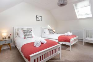 a bedroom with two beds with red and white sheets at Endymion in Porthtowan