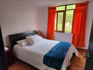 a bedroom with a bed and a window with red curtains at Casa Mirador Alojamiento Campestre in Filandia