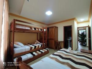 a bedroom with three bunk beds and a desk at Hostal El Eden de Mindo in Mindo