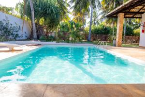 - une piscine d'eau bleue avec des palmiers dans l'établissement Refugios Parajuru - Casa Pequena, à Parajuru