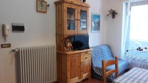 Habitación con armario de madera y TV. en Casa di Giulia en Champoluc