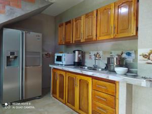 a kitchen with wooden cabinets and a stainless steel refrigerator at Hostal El Eden de Mindo in Mindo