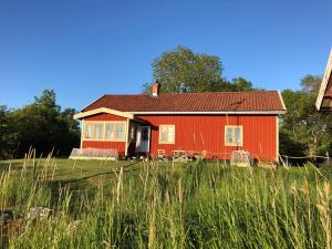 uma casa vermelha num campo de relva alta em Änden på Säby Tjörn em Säby