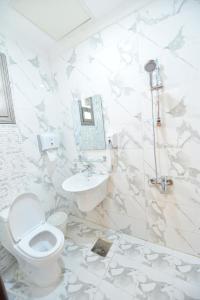 een witte badkamer met een toilet en een wastafel bij الدانة للشقق الفندقية in Koeweit