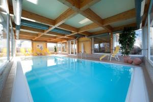 a large swimming pool in a hotel with a wooden ceiling at Hotel Godewind in Warnemünde