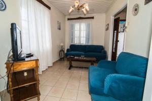 a living room with blue couches and a tv at Avli Townhouse in Panormos Skopelos