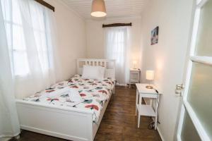 a white bedroom with a bed and a table at Avli Townhouse in Panormos Skopelos
