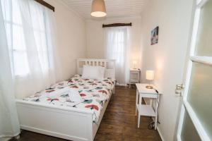 een witte slaapkamer met een bed en een tafel bij Avli Townhouse in Skopelos Town