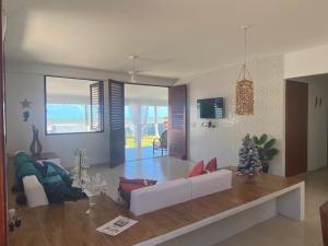 ein Wohnzimmer mit einer weißen Couch und einem Tisch in der Unterkunft Casa Pé na Areia in São José da Coroa Grande
