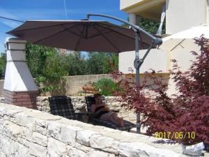a woman sitting in a chair under an umbrella at Vita Garden Apartment 85 m2 Private Entrance & 100 m2 Terrace in Pula