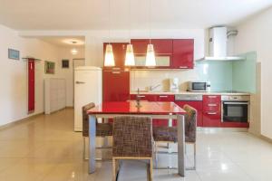 a kitchen with red cabinets and a red table and chairs at Vita Garden Apartment 85 m2 Private Entrance & 100 m2 Terrace in Pula +3 photos