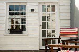 a white house with a door and two chairs at No. 3 Bligh's Yard in Canterbury