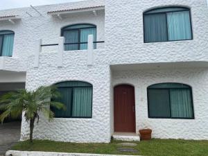 un edificio blanco con una puerta roja y una palmera en Villa c-Netflix, Alberca y vista al Rio, en Veracruz
