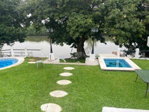 un patio trasero con piscina y un árbol en Villa c-Netflix, Alberca y vista al Rio, en Veracruz