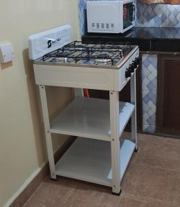 a kitchen stove with a microwave on top of it at Pearl suites in Bungoma