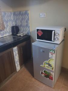 einen kleinen Kühlschrank mit einer Mikrowelle darüber in der Unterkunft Pearl suites in Bungoma