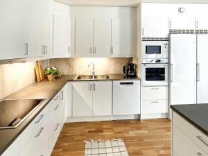 una cocina blanca con armarios blancos y fregadero en Holiday home VIKBOLANDET II en Arkösund