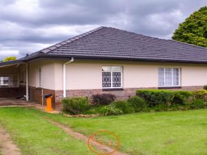 a white house with a black roof and a yard at Slee Guest House in Howick