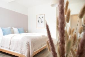um quarto com uma cama com lençóis brancos e almofadas azuis em Löwe Apartments "Blau" Neuhausen am Rheinfall em Neuhausen am Rheinfall
