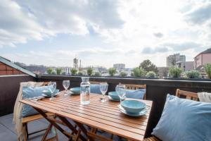 une table en bois avec des verres et des assiettes sur un balcon dans l'établissement Löwe Apartments "Blau" Neuhausen am Rheinfall, à Neuhausen am Rheinfall