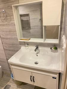La salle de bains est pourvue d'un lavabo blanc et d'un miroir. dans l'établissement أزار للشقق الفندقية, à Abyār ‘Alī