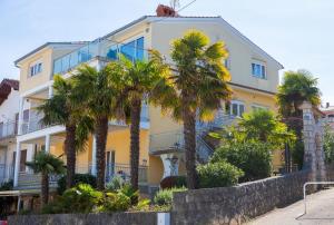 a yellow building with palm trees in front of it at Luxury apartment Vanessa, Njivice in Njivice