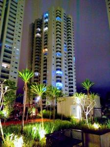 a large building with palm trees in front of it at Flat de luxo São Paulo - Guarulhos in Guarulhos