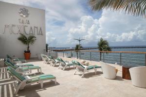 a row of lounge chairs on a balcony with the ocean at Casa Mexicana Cozumel in Cozumel