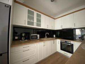 una cucina con armadi bianchi, lavandino e forno a microonde di Central Park Apartment a Cluj-Napoca