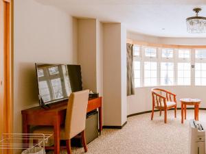 a living room with a television and a table and chairs at Hakuba Sun Valley Hotel Annex - Vacation STAY 90355v in Iida